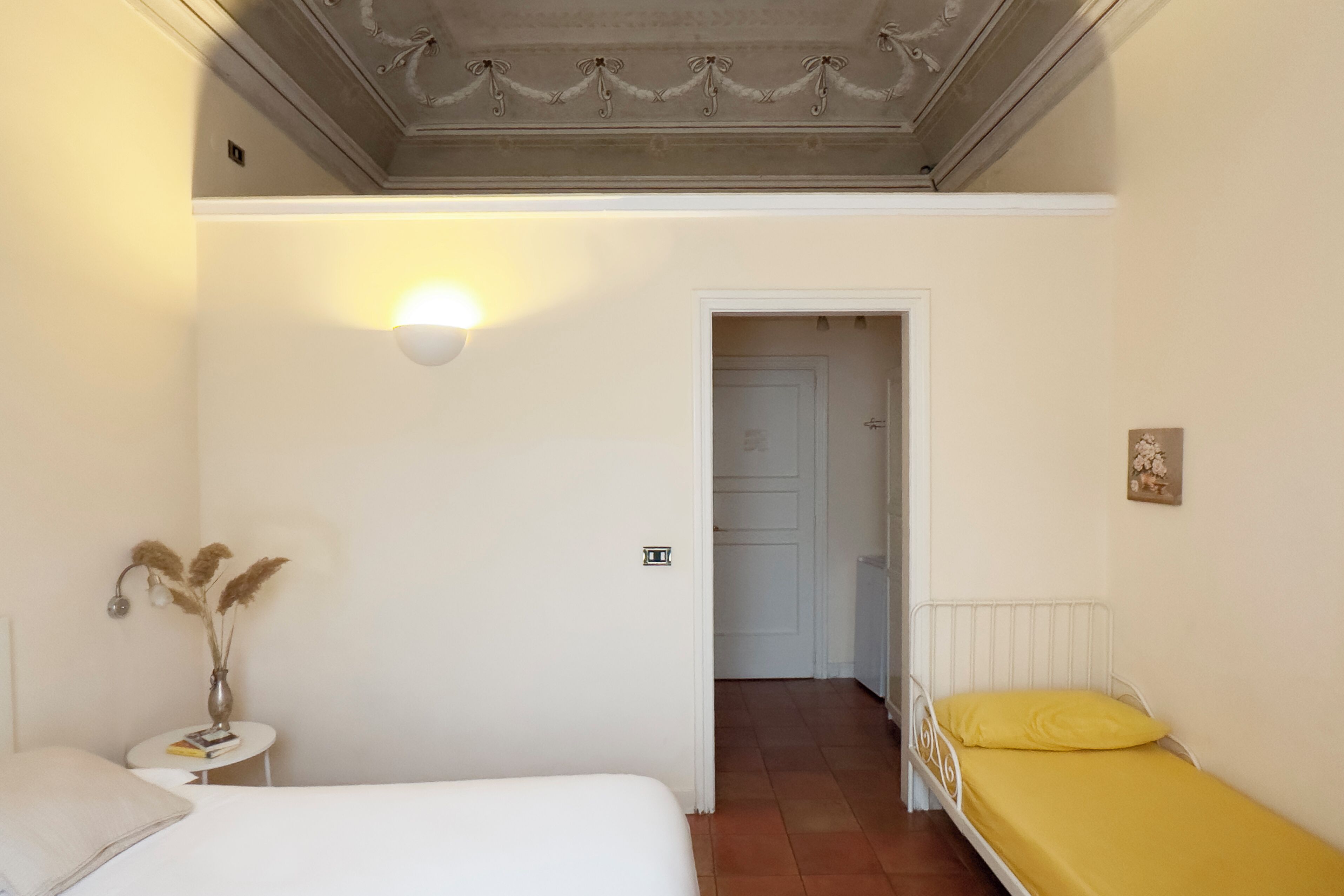 Une chambre à coucher comprenant un lit, une table de chevet, une lampe et une porte donnant sur une autre pièce.