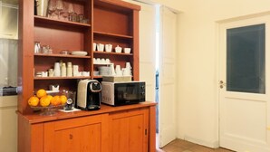 Una cocina con un armario de madera que contiene vajilla, un microondas y una cafetera.