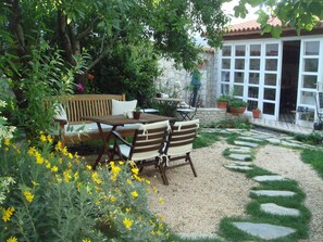 A patio with a wooden table and chairs, surrounded by potted plants and yellow flowers. - Incirliev - Special Class (Cesme)