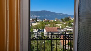 Ein Balkon mit Blick auf eine Stadt, ein Gebirge und ein Gewässer.