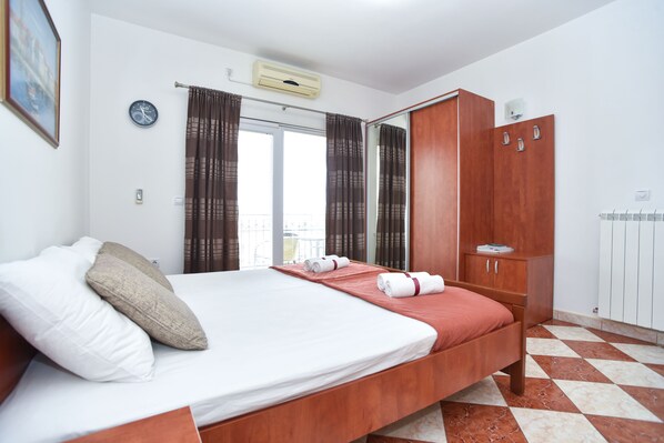 A hotel room with a bed, a wardrobe, a radiator, and a clock on the wall.