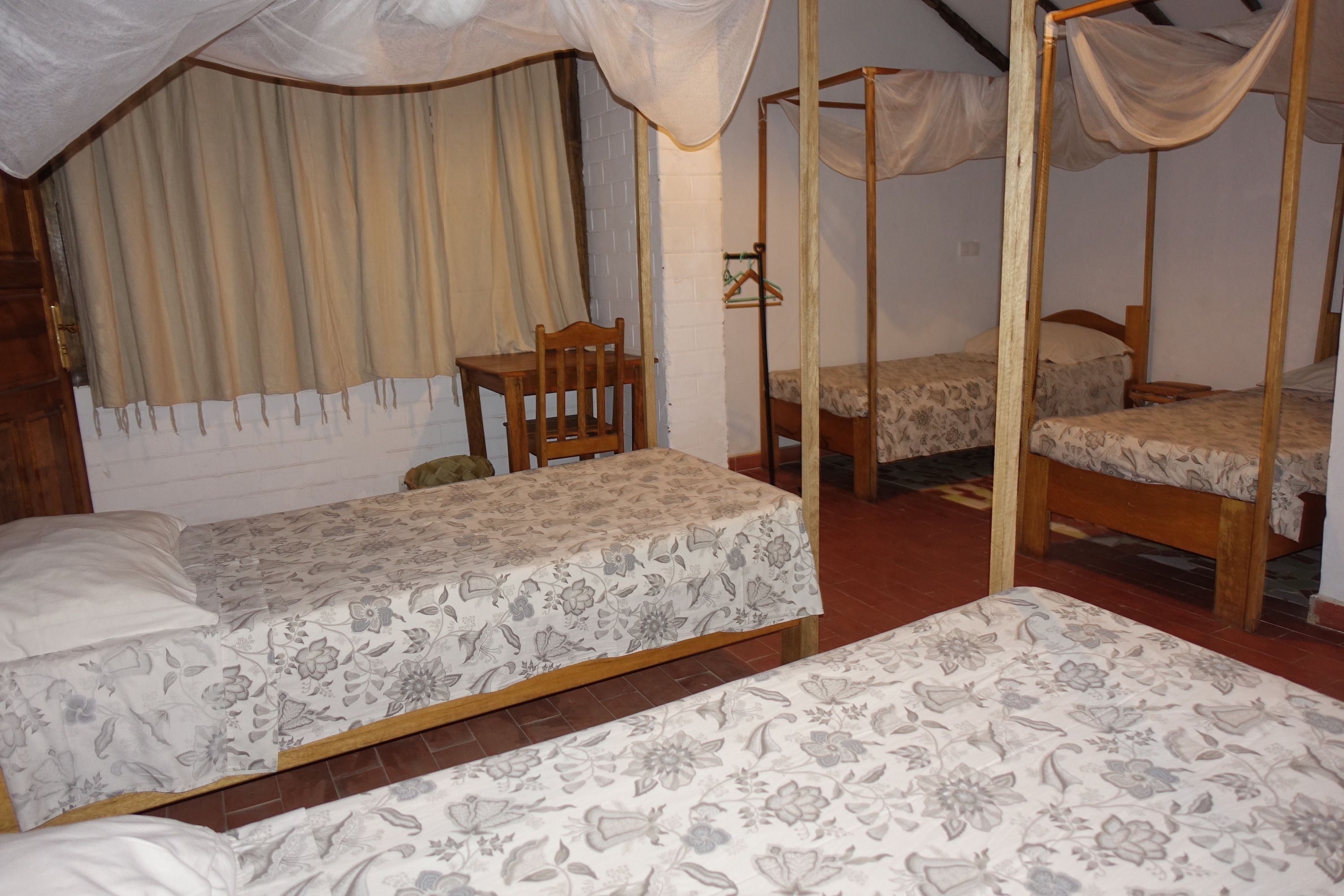 A room with two single beds, a wooden chair, and a small table.