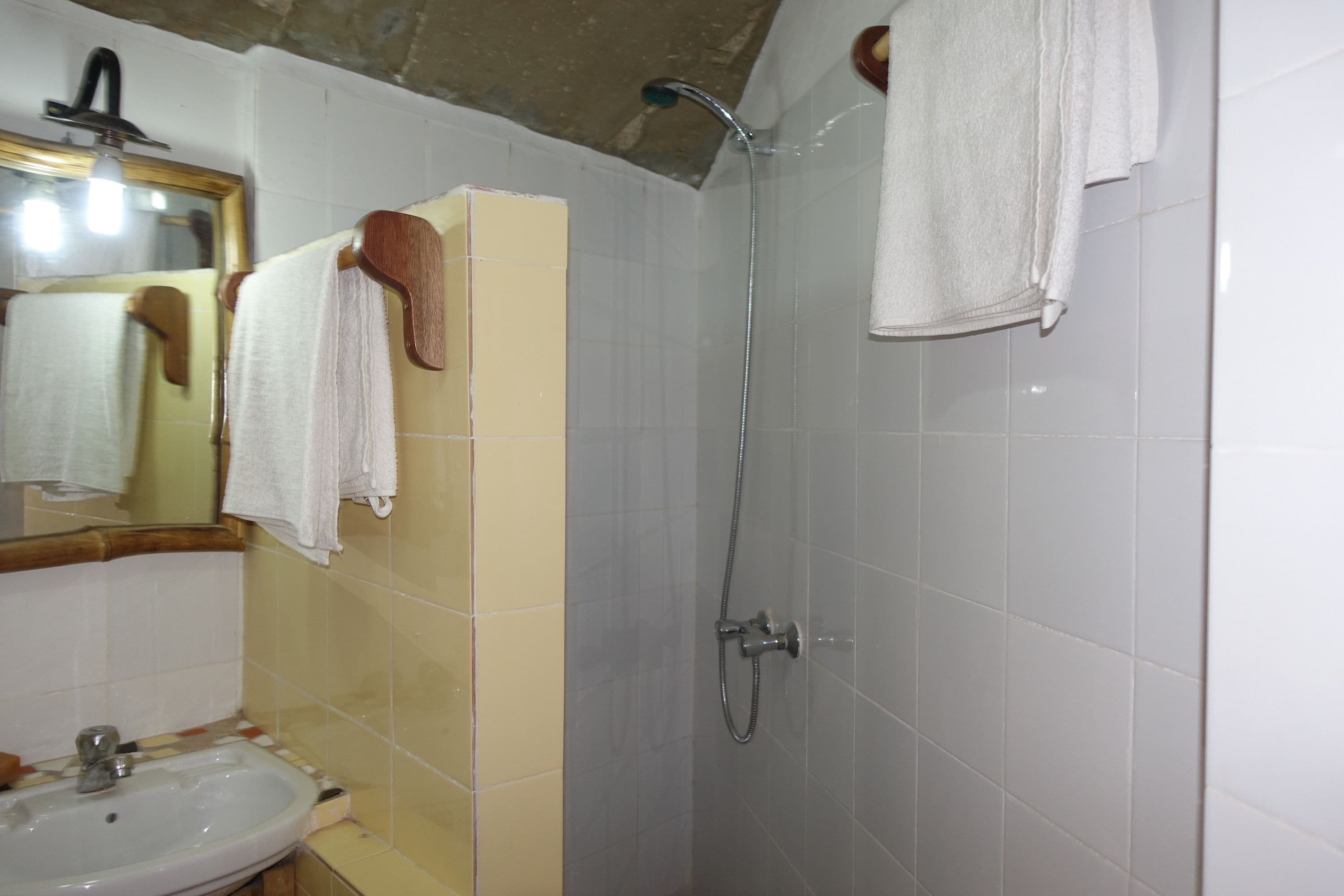 A bathroom with a sink, mirror, shower, and towels.