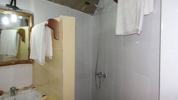 A bathroom with a sink, mirror, shower, and towels.