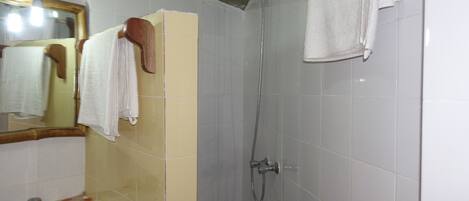 A bathroom with a sink, mirror, shower, and towels.