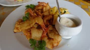 A plate of fried shrimp and potatoes with a small bowl of sauce.