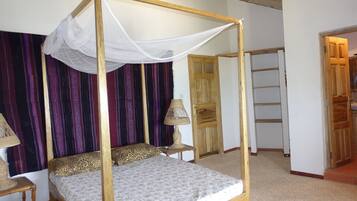 A four-poster bed with a canopy, a wooden wardrobe, and a small bedside table with a lamp.