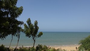 A beach with clear skies, calm water, and a few people walking. - Keur Marrakis (Mbour)