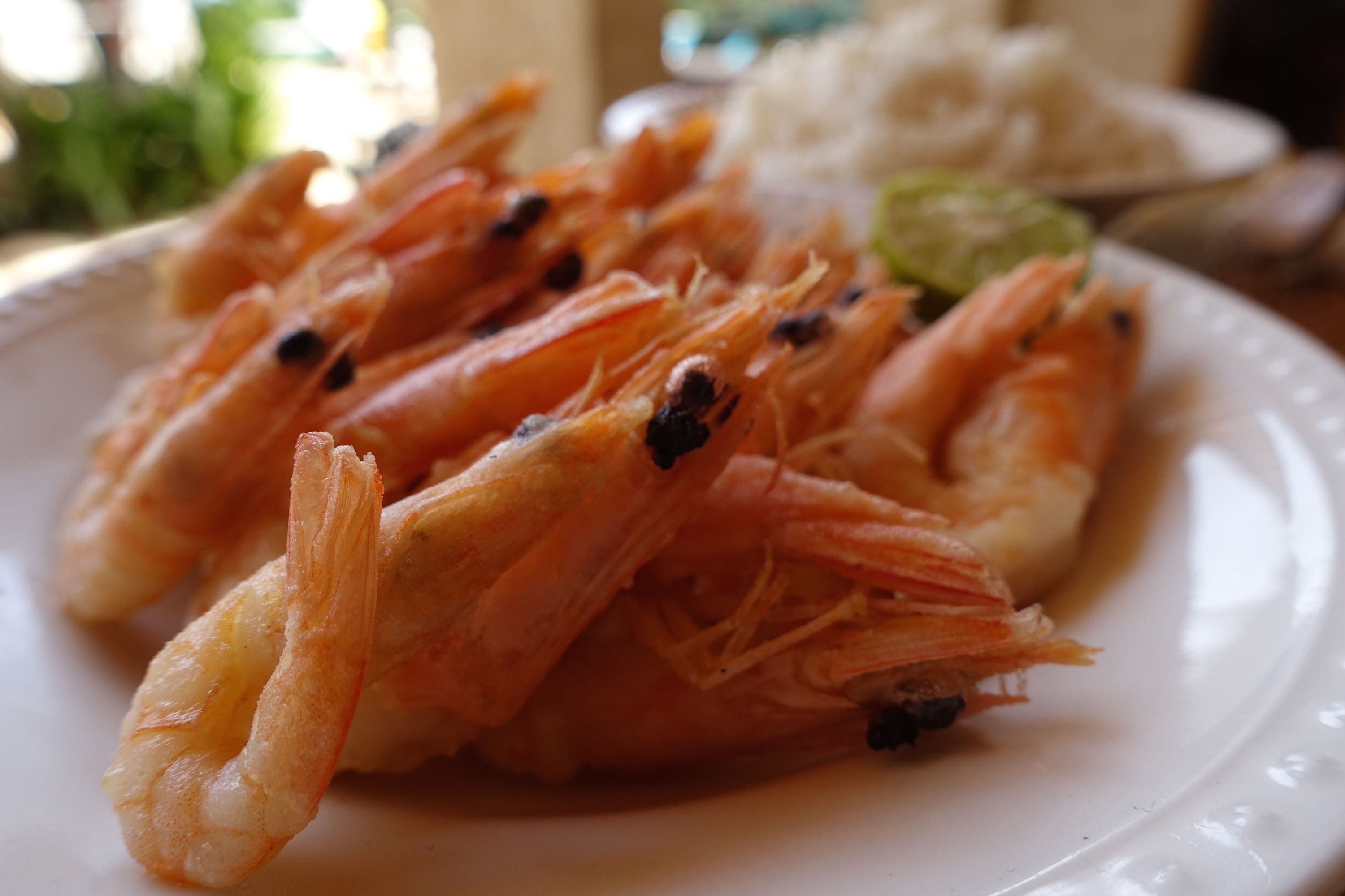 A plate of cooked shrimp with a garnish of green leaves.