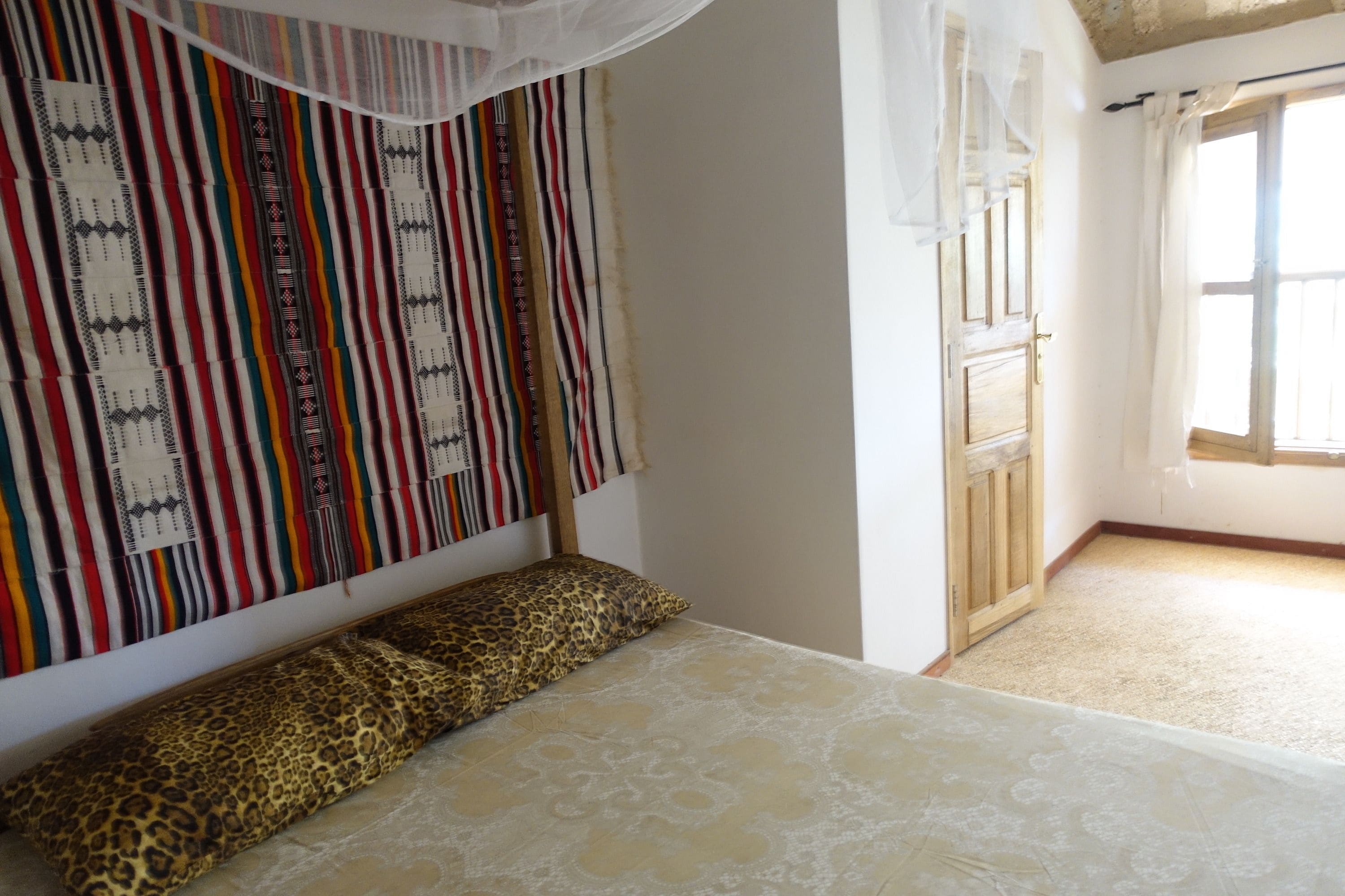 Une chambre avec un lit, des rideaux à motifs et une vue sur l’extérieur.