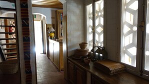 A kitchen with a wooden counter, a window with a geometric pattern, and a door leading to another room. - Keur Marrakis (Mbour)