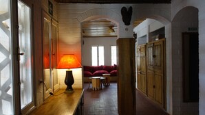 A hallway with a wooden floor, a red sofa, and a lamp. - Keur Marrakis (Mbour)