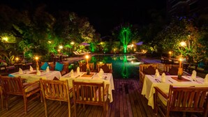 An outdoor dining area with tables and chairs, a pool, and trees.