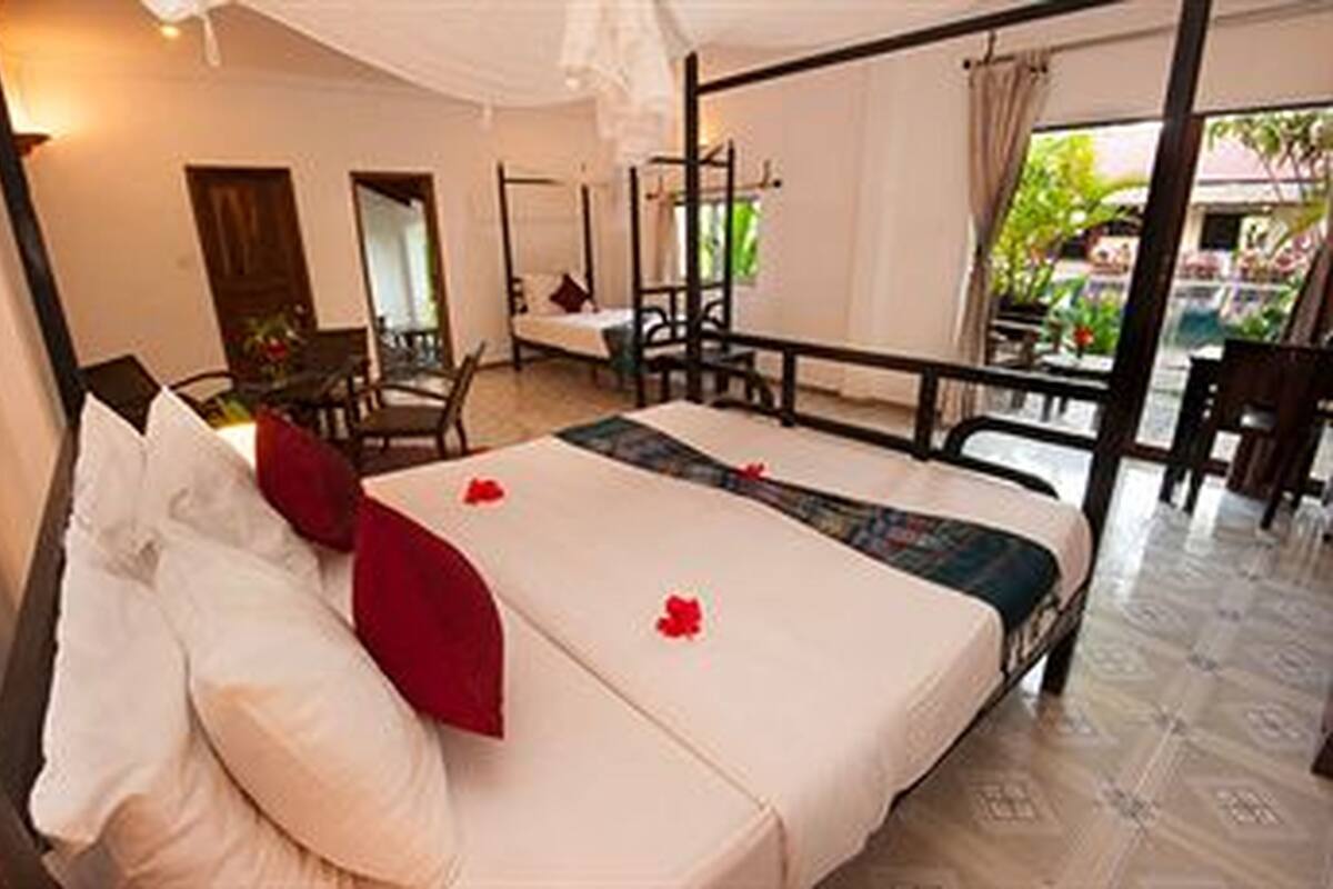A bedroom with a bed, a desk, and a chair. There is a window with curtains.