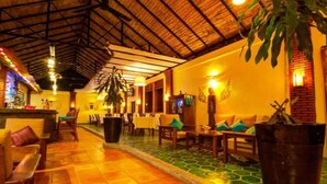 A spacious indoor area with a high ceiling, tiled flooring, and a variety of seating arrangements including sofas and chairs.