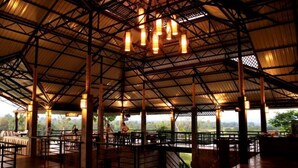 An indoor dining area with a high ceiling and metal beams, featuring tables and chairs arranged for dining. - Chiangmai Inthanon Golf and Natural Resort (Doi Lo)
