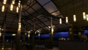 An indoor space with a high ceiling and metal beams, featuring hanging lights and a counter area with a sign that reads "LOUKOR". - Chiangmai Inthanon Golf and Natural Resort (Doi Lo)