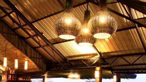 A cozy lounge area with wicker furniture, a circular seating arrangement, and hanging pendant lights. - Chiangmai Inthanon Golf and Natural Resort (Doi Lo)