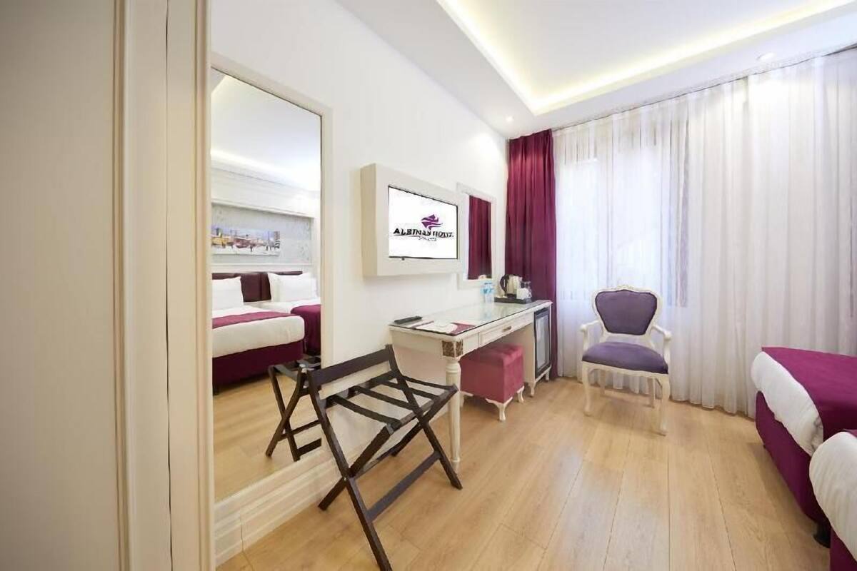 Una habitación de hotel con cama, escritorio, silla y televisor montado en la pared.