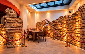 A dining area with a high ceiling and skylight, surrounded by walls of stacked pottery. - Albinas Hotel Old City (Istanbul)