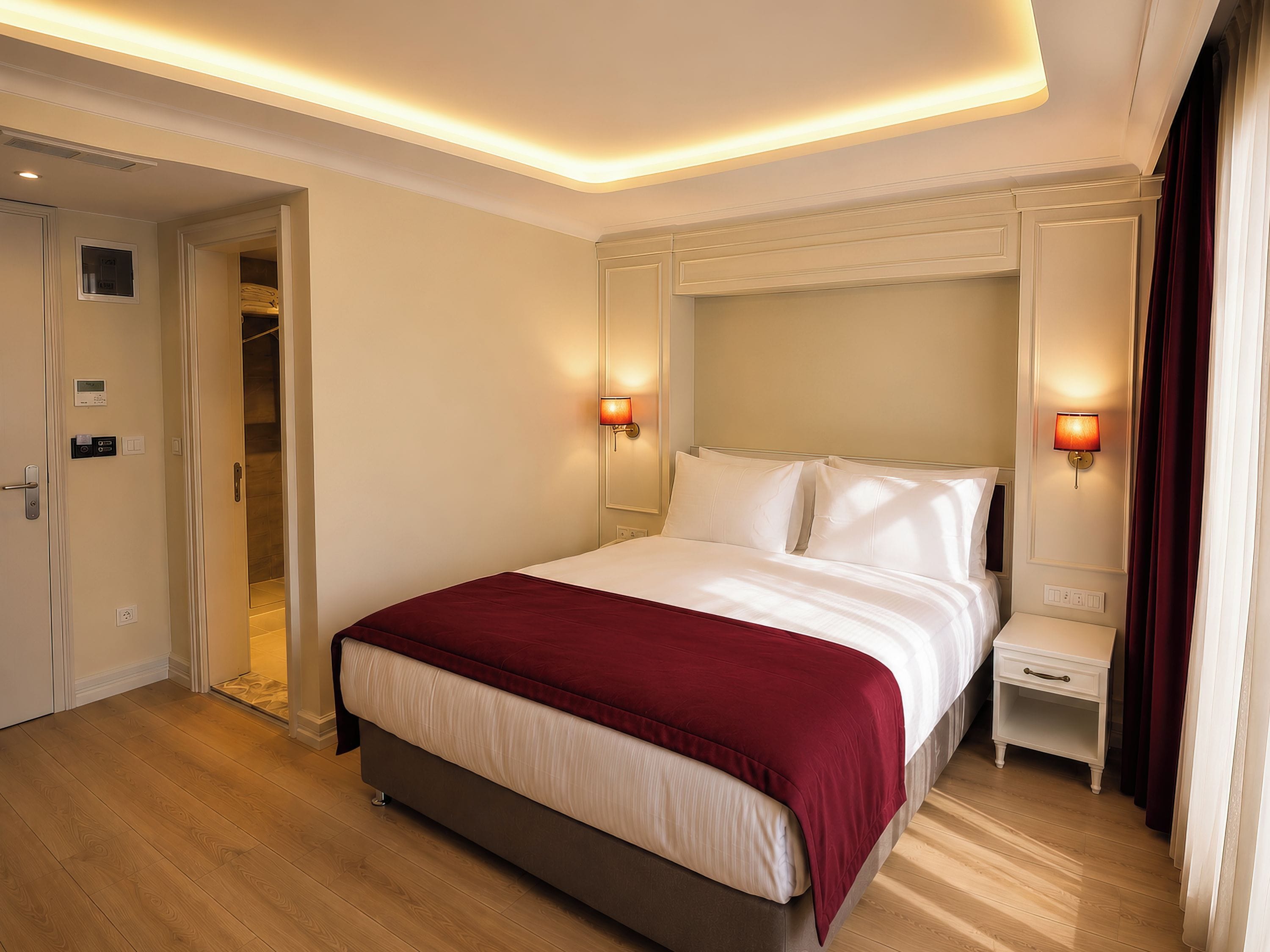 A hotel room with a bed, bedside tables, a wardrobe, and a mirror.