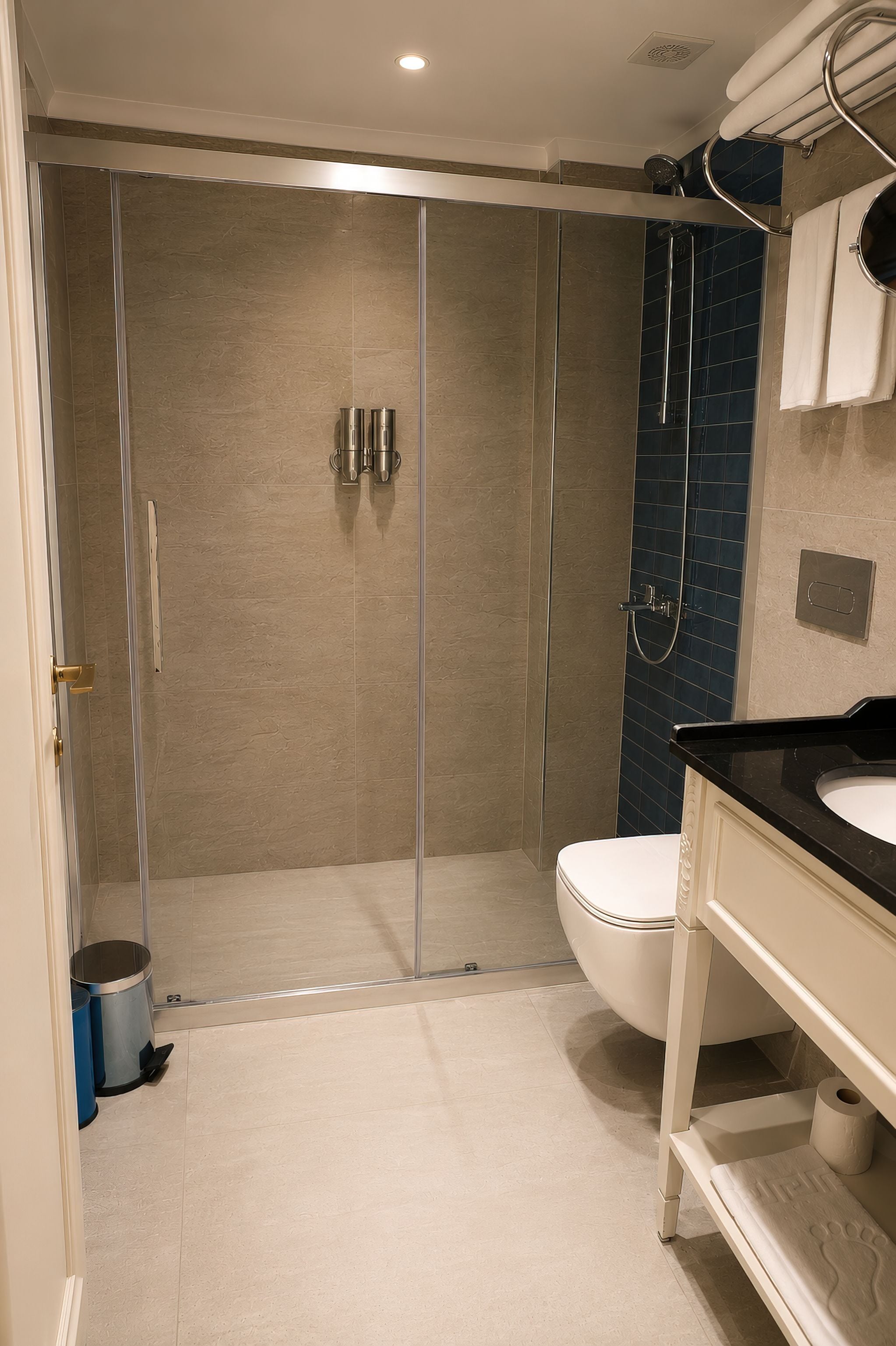 A modern bathroom with a glass-enclosed shower, a white toilet, and a black countertop.