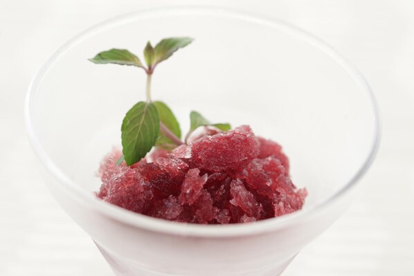 A clear glass bowl containing a pinkish-red granular substance, possibly a dessert or condiment, with a sprig of mint on top. - Nasu Sunlight Hotel (Nasu)