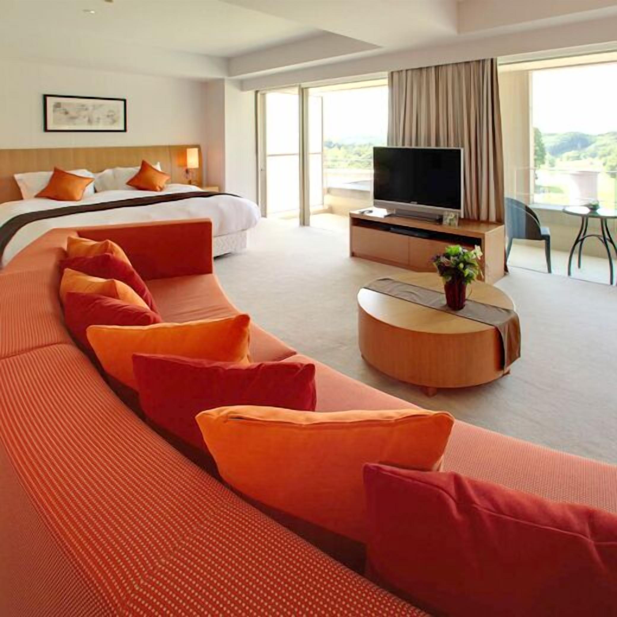 Camera d'albergo moderna con un letto grande, un divano, una TV e un'area pranzo.