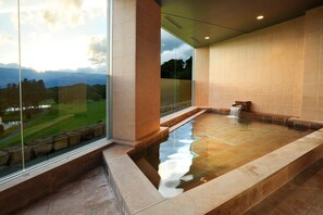 A modern spa with a large glass window, a hot tub, and a view of a golf course. - Nasu Sunlight Hotel (Nasu)