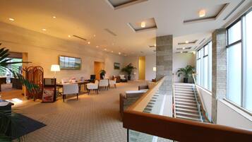 A spacious lobby with a staircase, seating area, and large windows.