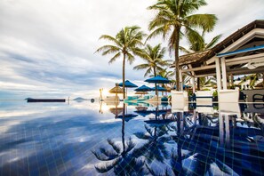 An infinity pool with palm trees and umbrellas, reflecting the sky and surroundings. - Sunrise Premium Resort Hoi An (Hoi An)