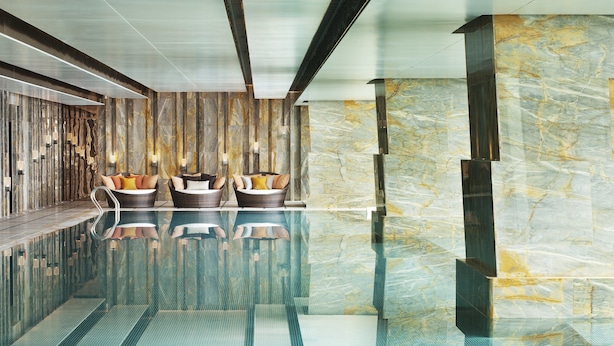 A modern indoor pool area with two wicker lounge chairs and a marble wall. - The St. Regis Shenzhen (Shenzhen)