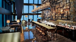 A spacious bar area with a long counter, multiple seating options, and a wall adorned with framed photographs. - The St. Regis Shenzhen (Shenzhen)