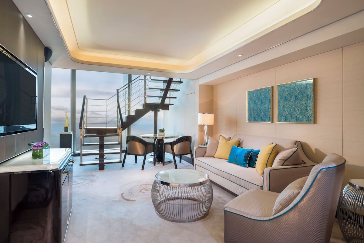 A modern living room with a sofa, coffee table, and TV. There's a staircase leading to an upper level.