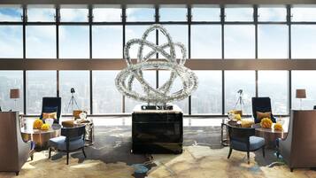 A high-rise hotel room with a large city view, a modern chandelier, and contemporary furnishings.