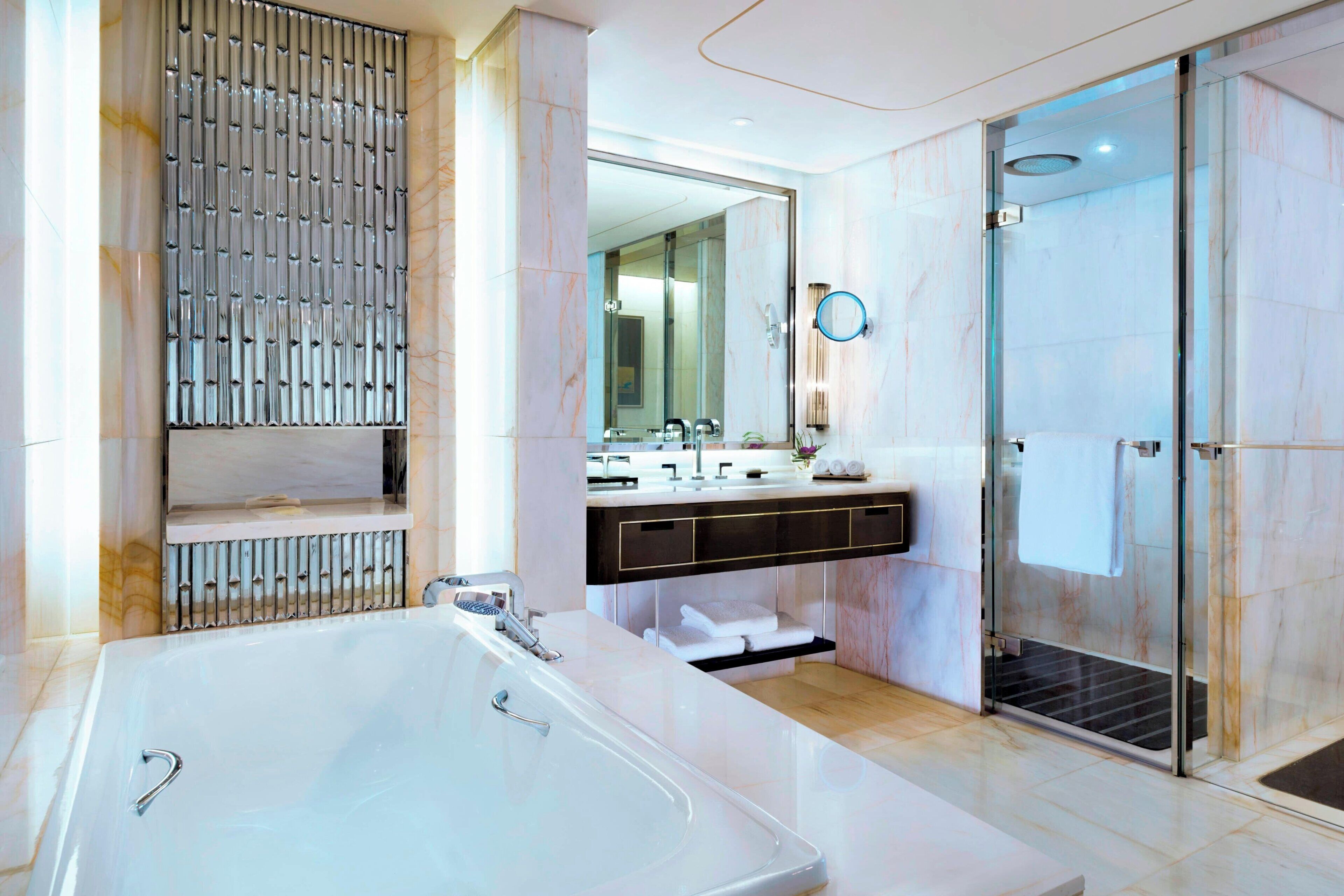 A modern bathroom with a large bathtub, a glass shower enclosure, and a vanity with a mirror.