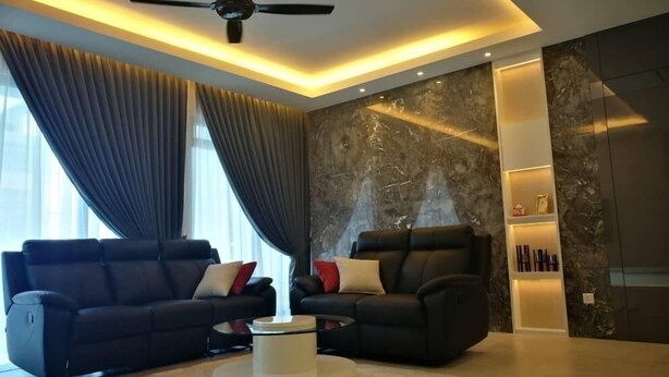 A modern living room with a ceiling fan, two black sofas with red and white cushions, a round coffee table, and a marble-patterned wall. - Casa Blanca Guest House (Malacca City)