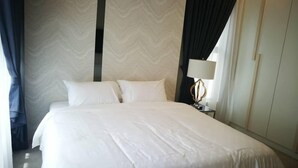 A hotel room with a large bed, a nightstand with a lamp, and a wardrobe. - Casa Blanca Guest House (Malacca City)