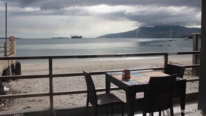 A beachside restaurant with a view of the sea, featuring outdoor seating and a pergola. - Subic Grand Seas Resort (Olongapo)