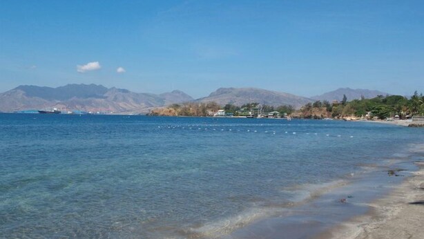 A coastal scene with clear water, a sandy beach, and mountains in the background. - Subic Grand Seas Resort (Olongapo)