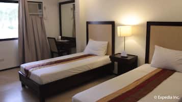 A hotel room with two beds, a desk, and a chair.