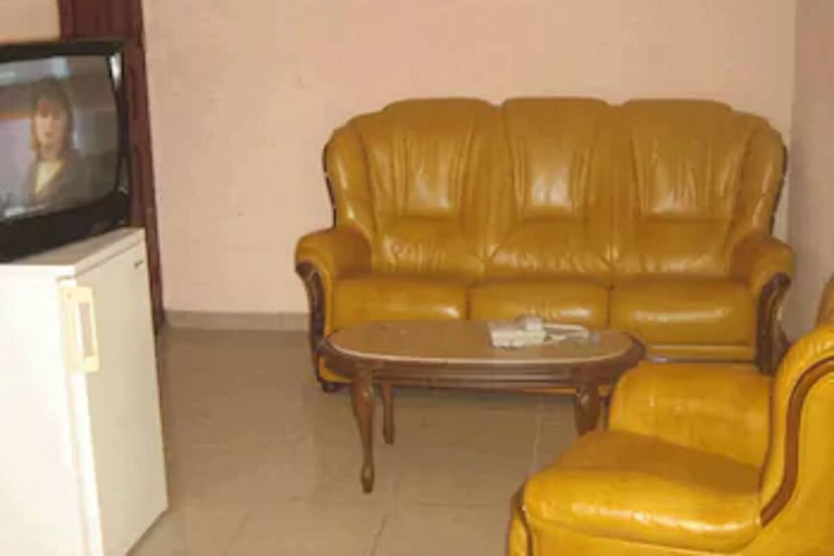 A living room with a yellow leather sofa, a wooden coffee table, and a television on a white cabinet.