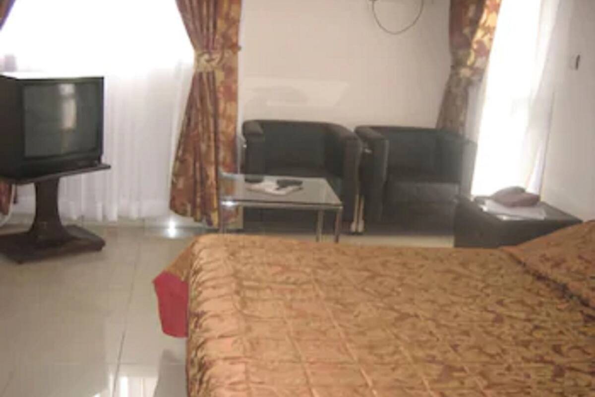 A hotel room with a bed, a television, a small table, and a chair.
