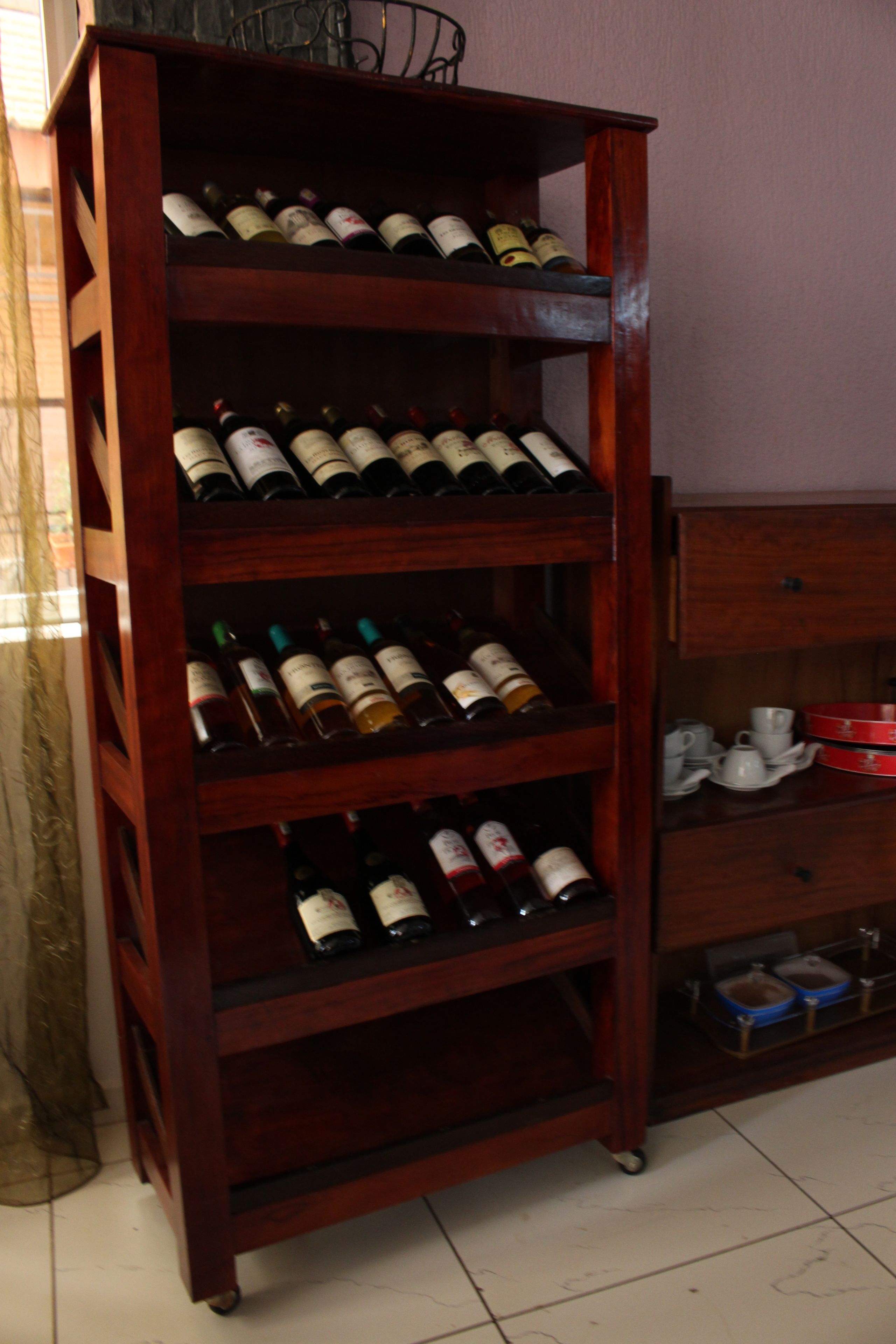 A wooden wine rack with multiple shelves holding wine bottles.