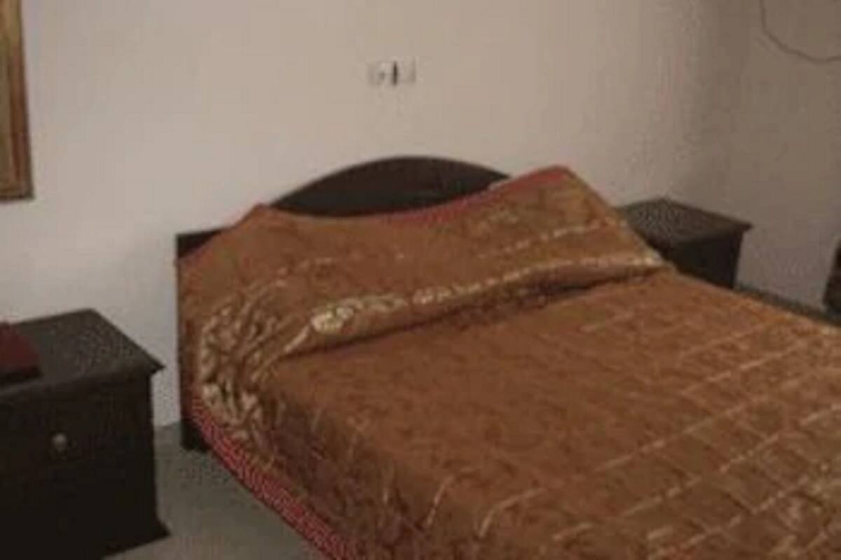 A bedroom with a bed, a nightstand, and a wall socket.
