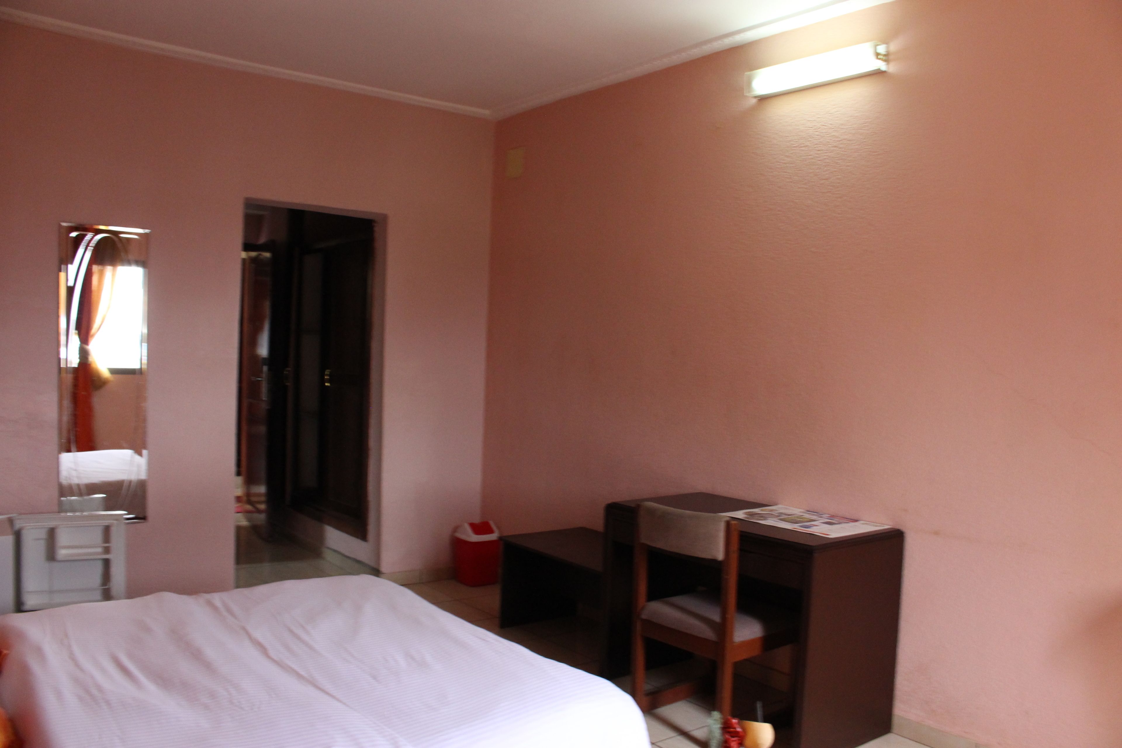 Una habitación de hotel con una cama, un escritorio, una silla, una mesita y un cubo de basura.