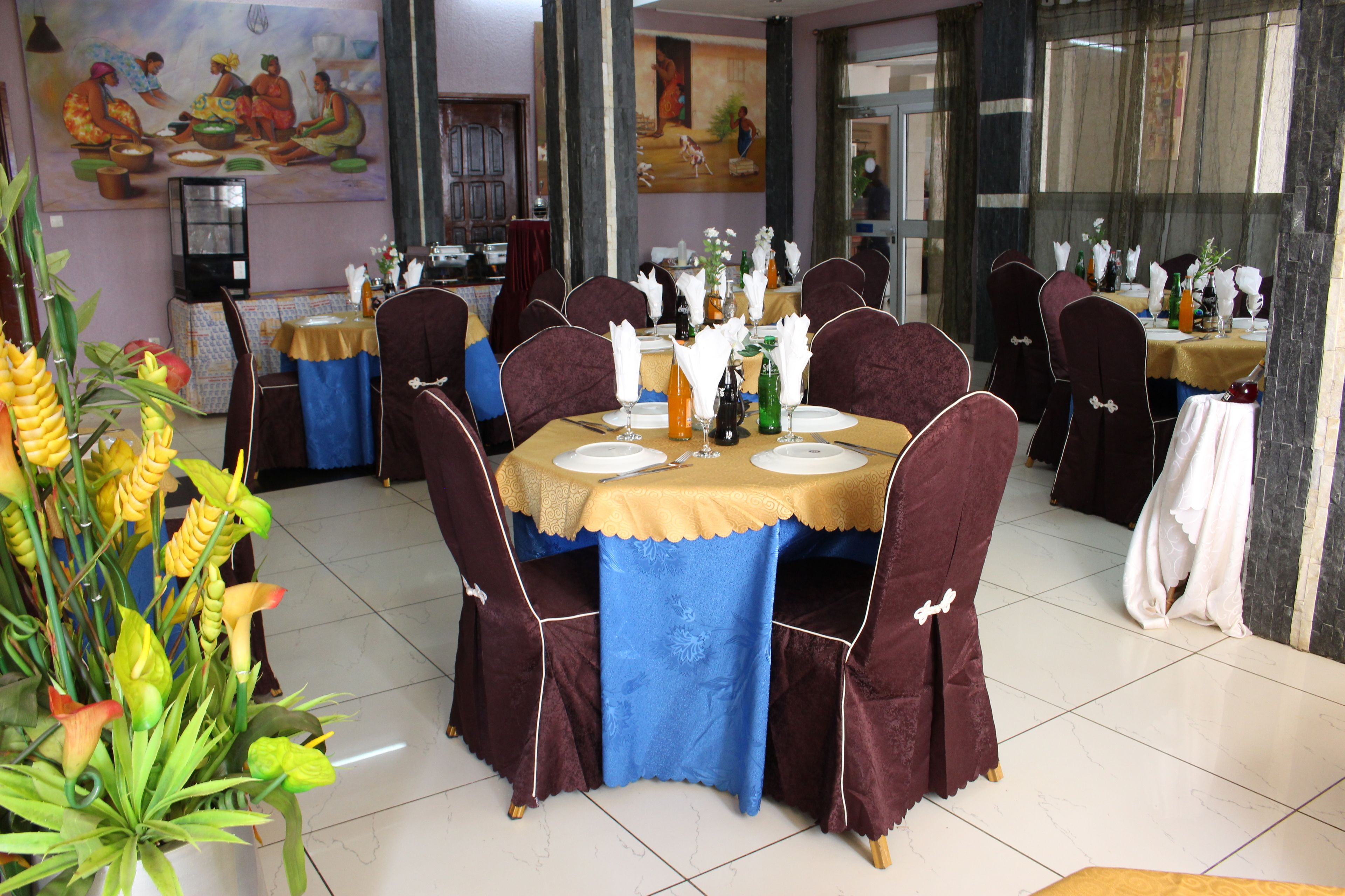 A dining area with round tables, chairs, and a variety of table settings.