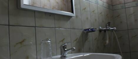 Un baño con lavamanos, espejo y ducha.