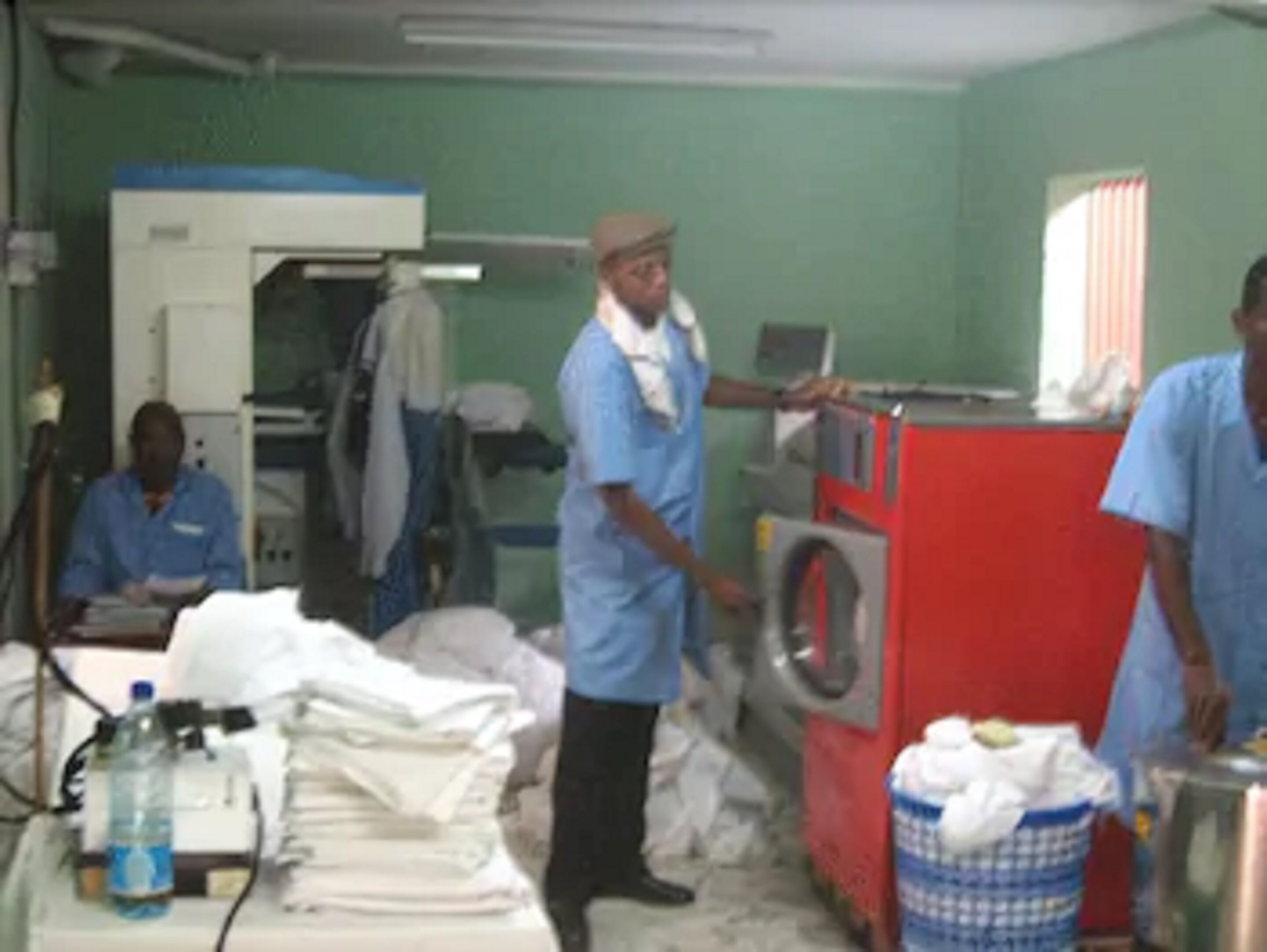A laundry room with a washing machine, a dryer, and a stack of folded clothes.