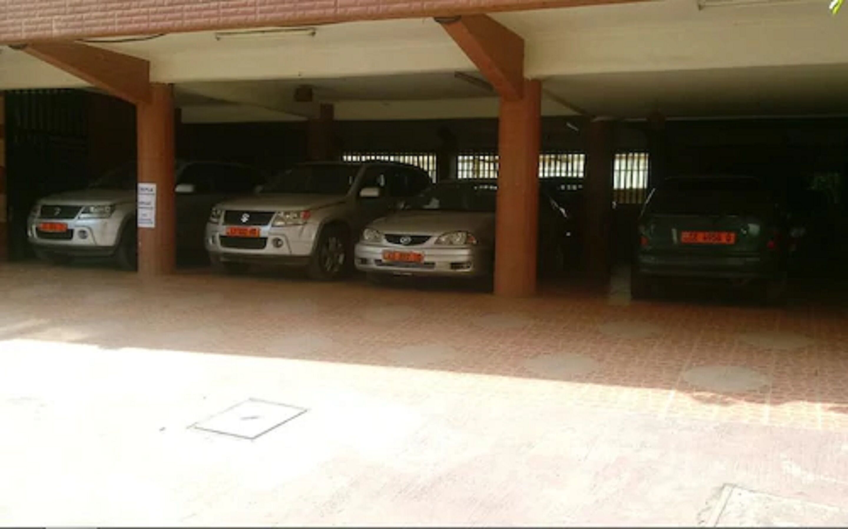A covered parking area with three cars parked under a roof.